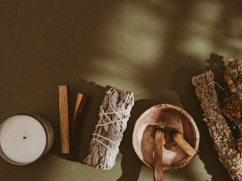 Items For Spiritual Cleansing - Sage And Flowers Bundle, Palo Santo Incense Sticks, White Candle On Green Background.