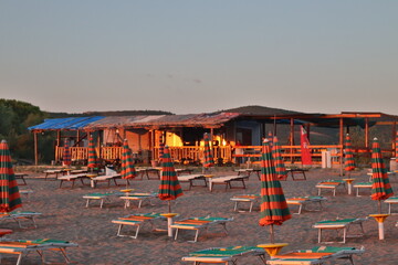 Albańska plażą z leżakami i domkiem letniskowym.