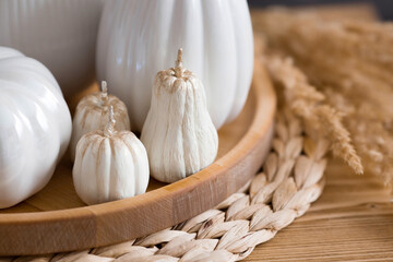 Still-life. White ceramic pumpkins, pampas grass, pumpkin-shaped candles on the coffee table in the...