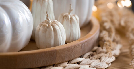 Still-life. White ceramic pumpkins, pampas grass, pumpkin-shaped candles on the coffee table in the home interior of the living room. Details of the decor. Cozy autumn concept.