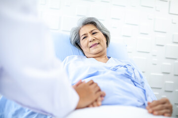 Asian doctor supporting and cheering up senior patient on bed in recover room. Healthcare and medicine concept.