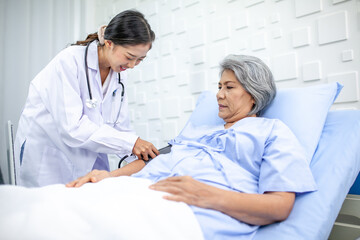 Beautiful asian doctor with stethoscope and document folder, examine the symptom for patient in the recovery room. Healthcare and medicine concept. - 531461386