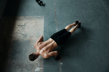 Top view of young muscular man doing push-up exercises in gym