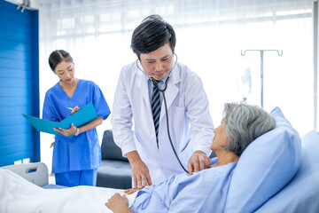 doctor visiting ward have woman patient and check her with stethoscope on bed. Woman patient lying on hospital bed while doctor giving her checkup.