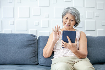 gray haired asian woman is holding smart phone using online apps or shopping online.