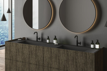 Corner of modern bathroom with gray walls, wooden floor, double sink and two round mirrors. Window with blurry view. 3d rendering