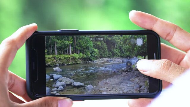 A Man's Hand Recording a River Video in the Nature