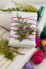 Original gift wrapping idea for Christmas. Recycled paper, colored wool threads and juniper twigs. Sustainable lifestyle, conscious consumption, zero waste.