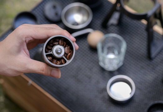 The barista slowbar holds a hand-cranked grinder with coffee beans inside.