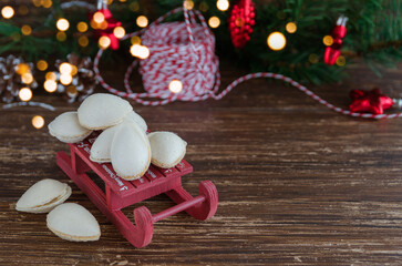 Spanish Christmas treat, Almendras rellenas or almond crisps filled with turron cream in the ceramic bowl with christmas tree and bokeh