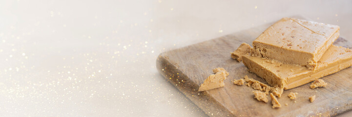 Traditional Christmas dessert banner. Almond nougat typically made of almond and honey on woddena cut board.Copy sapce