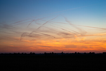 Many contrails in the evening sky, formed by the emission of water vapor from aircraft at high altitude