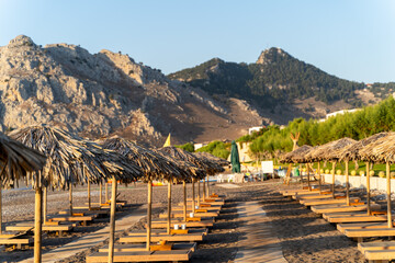 Wooden sunbeds with straw umbrellas on the beach