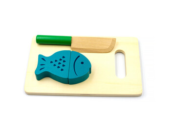 Wooden fish on magnets lies on a cutting board with a knife. Wooden toys for children