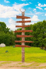A stylized wooden direction sign that points to animal enclosures.