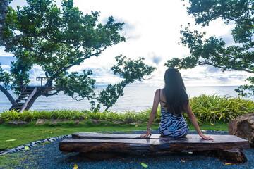chica sentada frente al mar en un banco de madera en el cafe LE JaoJom koh chang mirando al mar melancolicamente