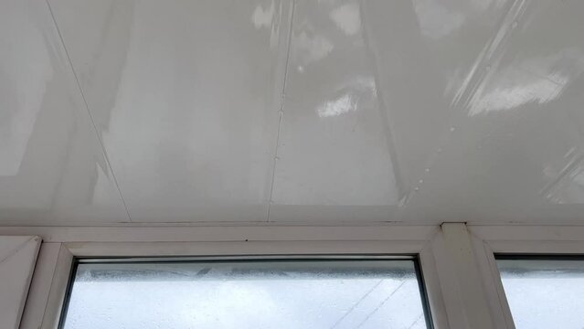 Due to a damaged roof during a heavy downpour, water flows through the ceiling into the middle of the house. Drops of water pass through the ceiling and drip onto the ground in the house. Water leakin