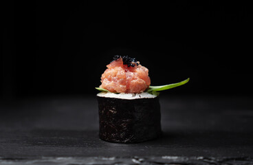 One sushi roll on black slate board