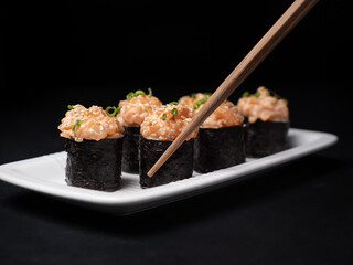 Take one sushi roll from black slate board using chopsticks