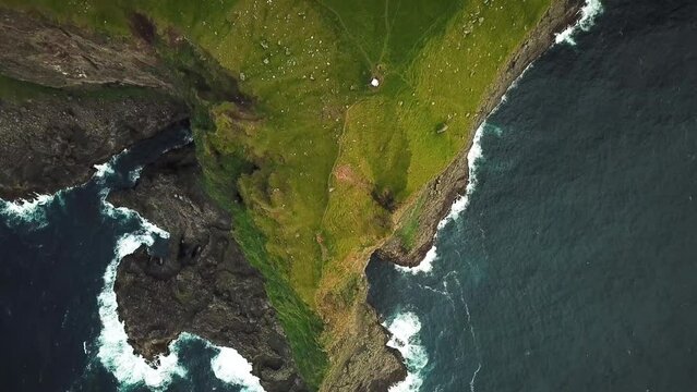 Aerial drone view of cliffs in Kalsoy island, Faroe Islands. Amazing Faroese nature, green hills and beautiful rocky cliffs and mountains. Kallur lighthouse. Sunny day in summer. Quality 4k footage.
