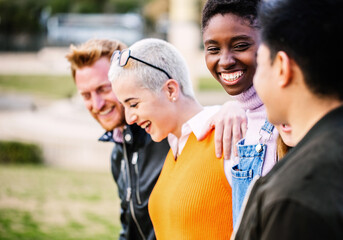 Diverse group of young people having fun together outdoor - Multiracial friendship concept with united men and women hugging each other in the city