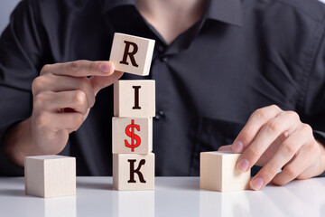 .a man's hand puts wooden cubes and makes up the word RISK, risk insurance, Risk taking, risk...