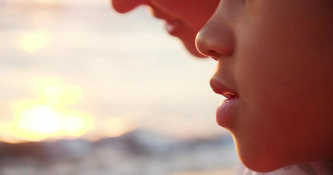 the lower part of the child's face, lips, an African-American kid in the light of the sun, close-up. Next to an adult woman, the mother of a child.
