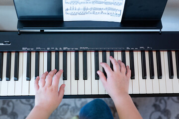 closeup musician child hands playing piano on piano keyboard. the concept of learning to play the piano. classical music. abstract music background.