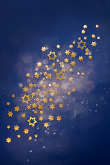 Golden Christmas stars on a defocused blue background with bokeh.