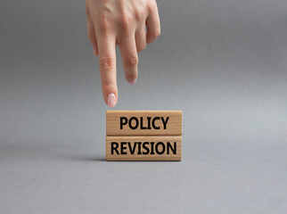 Policy revision symbol. Concept word Policy revision on wooden blocks. Beautiful grey background. Businessman hand. Business and Policy revision concept. Copy space
