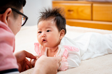 close-up Asian father, wearing a pink shirt, Father plays with his daughter gently, and cherishes...