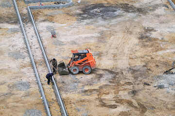 Excavator and workers laying curbs at a parking lot construction site