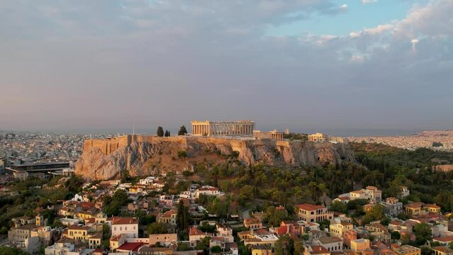 Aerial view Acropolis in Athens, Greece, sunrise in summer. Drone shot of golden sun rays hitting history rich Parthenon. Panorama of the Greek capital, flyover in the peaceful morning sea background