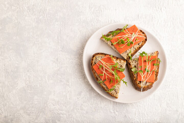 Grain bread sandwiches with red tomato cheese and microgreen on gray,  top view, copy space.