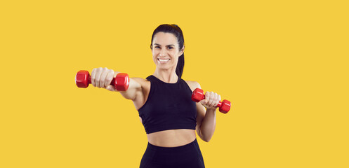 Wide banner portrait of smiling toned young woman coach in sportswear isolated on yellow studio...