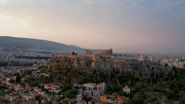 Aerial view Acropolis in Athens, Greece, sunrise in summer. Drone shot of golden sun rays hitting history rich Parthenon. Panorama of the Greek capital, flyover in the peaceful morning sea background