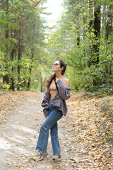 Portrait of romantic woman at fairy forest. A beautiful young girl with glasses is walking through the forest. Girl purple suit. Corduroy fabric