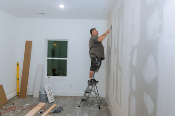 Worker the process trowels putty on drywall finishing putty with hand a spatula.