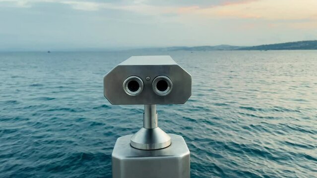 rear view closeup of coin operated aluminum metallic binoculars at the sea shore