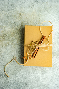 Overhead view of a rustic gift box tied with string and decorated with a fir branch cinnamon stick and star ornament