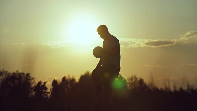 Slow motion video of a silhouette of a man kicking a ball. Training on the street in a football game. High quality 4k footage