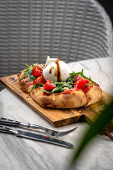 Italian focaccia with burrata and zucchini flower with tomatoes cherry and ham, flatlay top view composition, on a black background