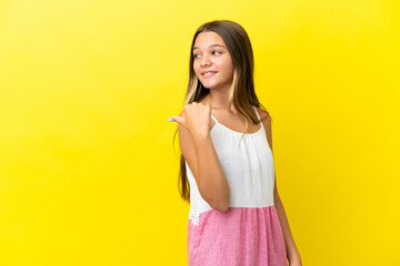 Little caucasian girl isolated on yellow background pointing to the side to present a product