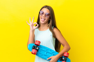 Little caucasian skater girl isolated on yellow background with a skate and doing OK sign