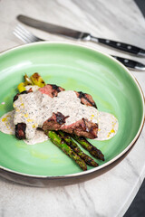 Roasted rib eye steak with green asparagus on old sheet