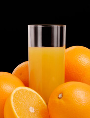 Orange juice glass on orange juice fruits on black background.