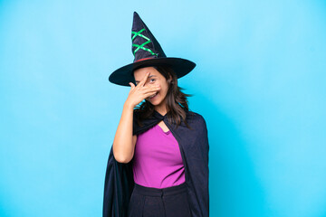 Young hispanic woman dressed as witch over isolated background covering eyes by hands and smiling