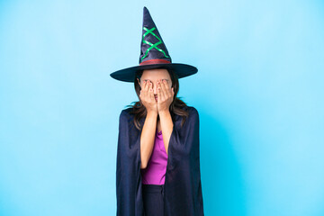 Young hispanic woman dressed as witch over isolated background covering eyes by hands