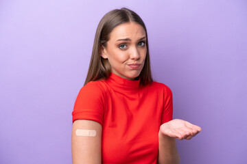 Young caucasian woman wearing band aid isolated on purple background making doubts gesture while...