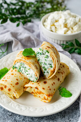 Pancakes stuffed with cottage cheese and herbs on a white plate